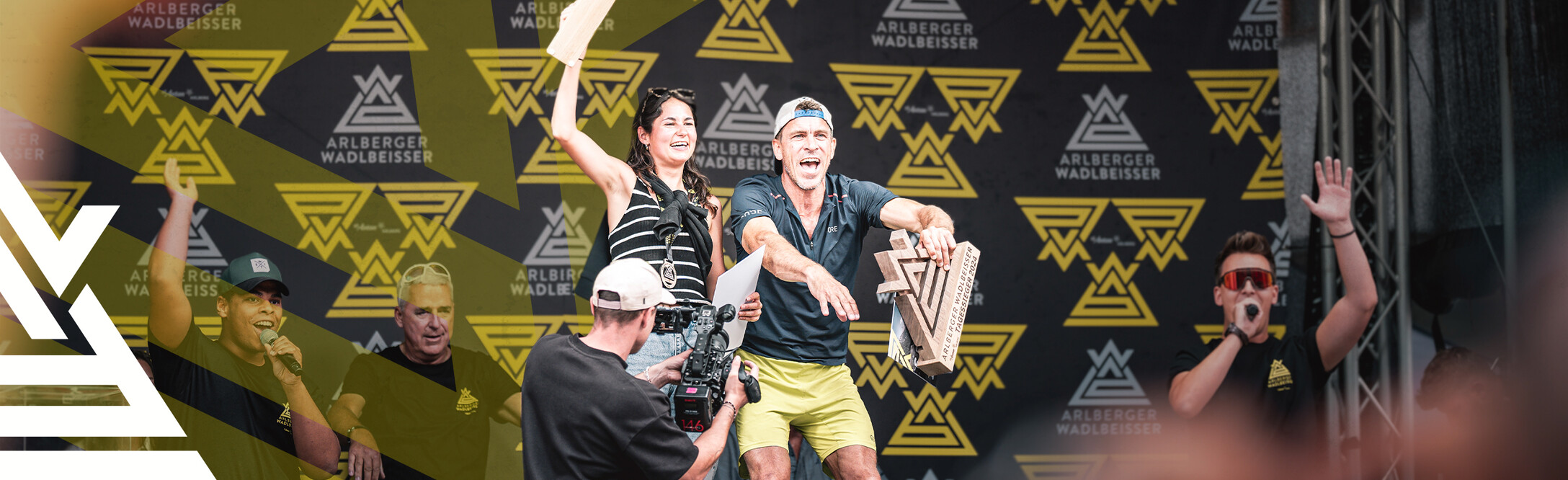 Arlberger Wadlbeisser - Preisvergabe 2024 Siegerin und Sieger des Arlberger Wadlbeisser 2024 auf der Bühne nach der Preisvergabe. Arlberger Wadlbeisser Logo als Designelemnt in weiß am linken Bildrand.