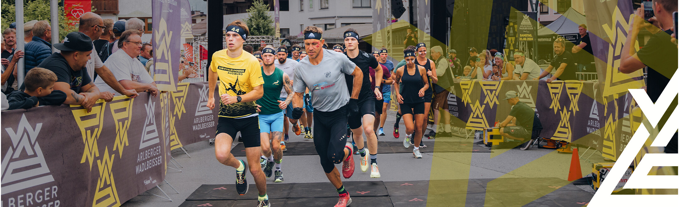 Starter:innen beim Arlberger Wadlbeisser auf den ersten Metern. Arlberger Wadlbeisser Logo als Designelemnt in weiß am rechten Bildrand.