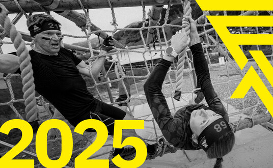  A group of athletes dressed in black are running towards the camera. ‘2025’ is written in yellow at the bottom right. The Arlberger Wadlbeisser logo can be seen as a design element at the top left.