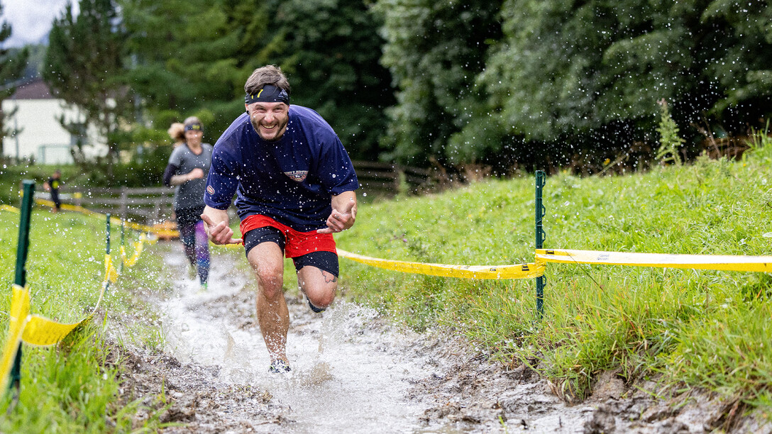 Sportler rennt durch einen kleinen Bach / Athlete runs through a small stream