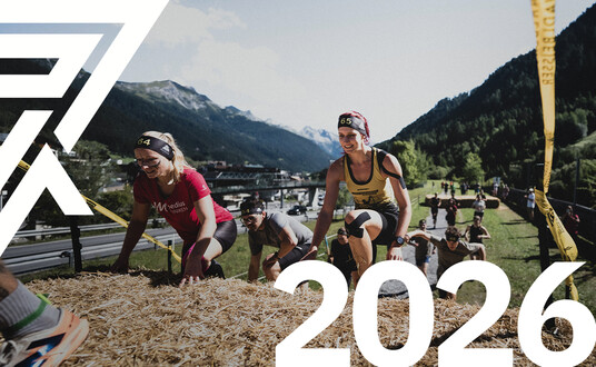 Athletinnen bezwingen das Hindernis Heureka. "2026" steht in weiß unten rechts geschrieben. Arlberger Wadlbeisser Logo ist als Designelement oben links zu sehen. 